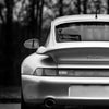 Photo noir et blanc de la face avant d'une voiture argentée sur fond sombre.