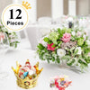 A gold crown candy box set of 12 with pink and white floral arrangements on a white table.