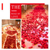 A close-up of a red carpet covered in artificial rose petals used for wedding decoration.