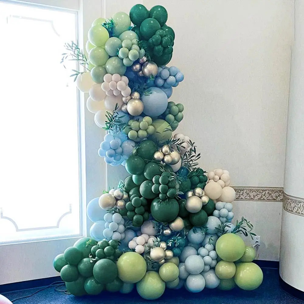 A large arrangement of latex balloons in shades of green and blue decorates a room.