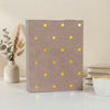 A brown laminated photo album with gold heart accents rests on a white surface.