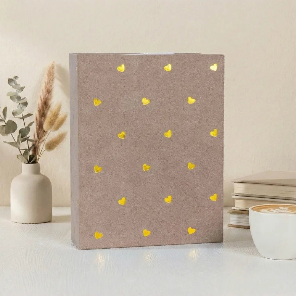 A brown laminated photo album with gold heart accents rests on a white surface.