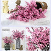 A bouquet of pink cherry blossoms and gypsophila artificial flowers displayed alongside a teddy bear.