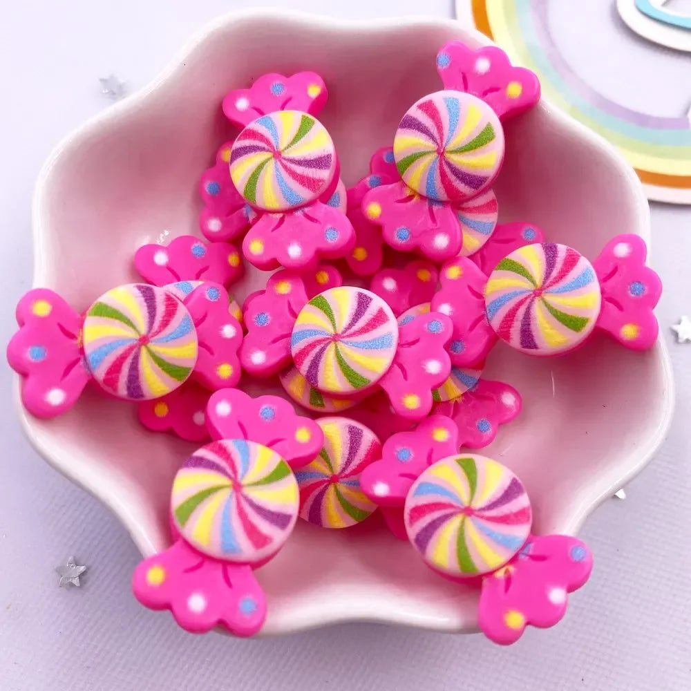 A pink bowl filled with colorful candy resin cabochons in various swirls of yellow, pink, and blue.