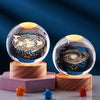 Galaxy crystal ball night light with a golden glow resting on a wooden base.