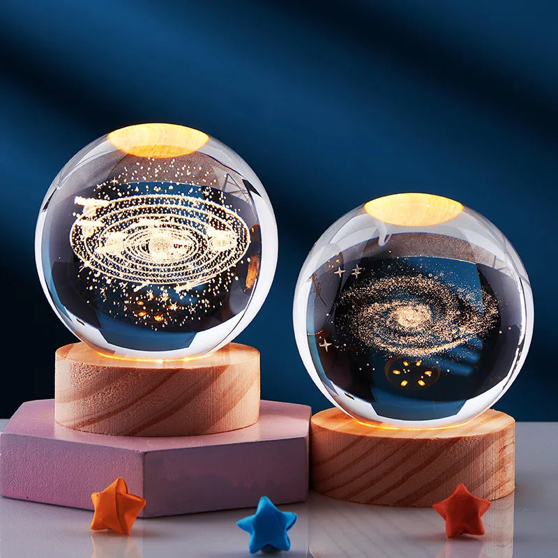 Galaxy crystal ball night light with a golden glow resting on a wooden base.