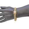A close-up of a gold Cuban link bracelet with a religious faith design worn on a dark hand.