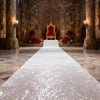Elegant white sparkling aisle runner leading down a stone church aisle with ornate throne chairs and pillars