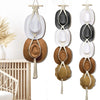 Bohemian macrame hat hanger with round woven hats displayed on a white wall.