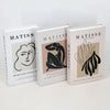 A set of three modern decorative fake books titled Matisse The Cutouts in white and beige covers.