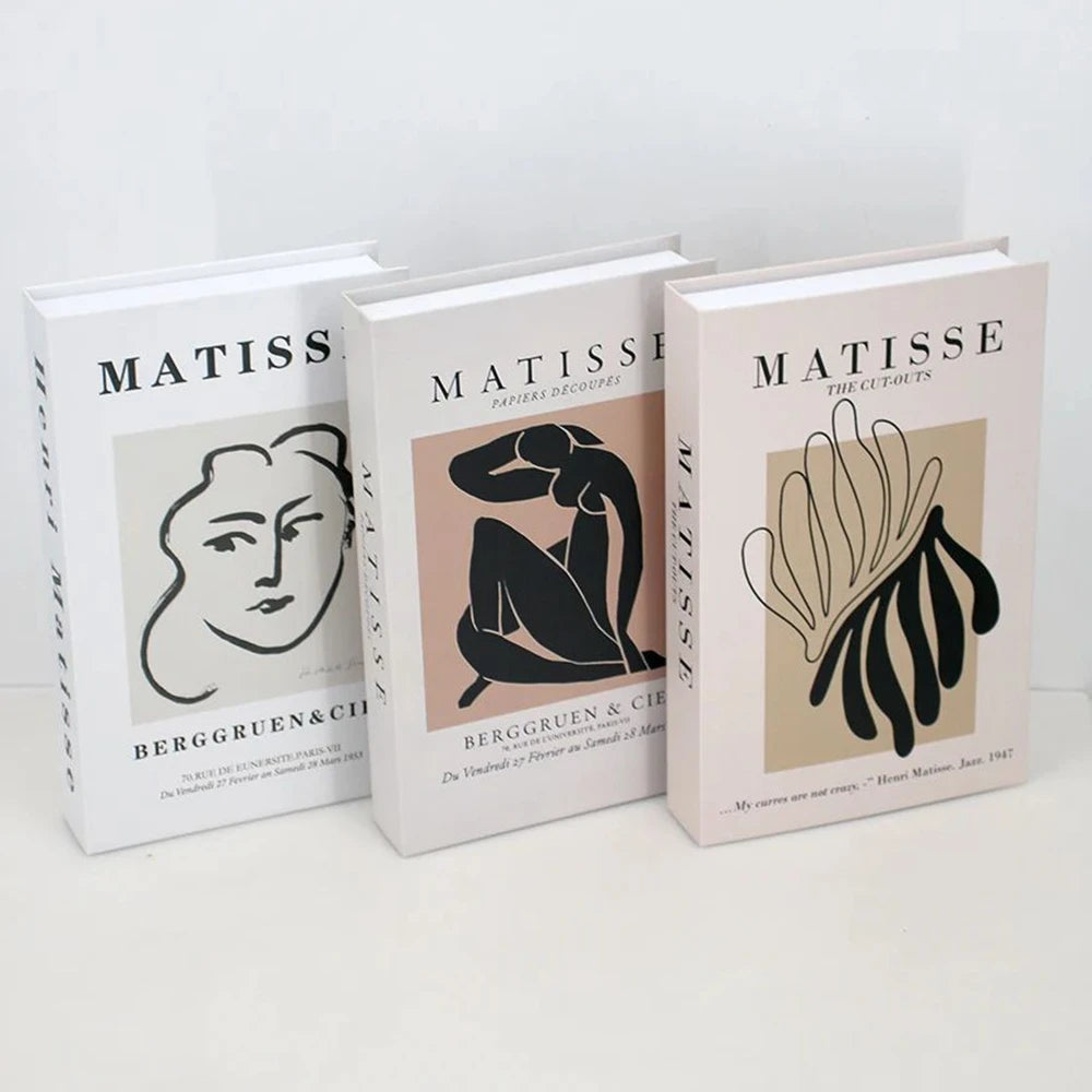 A set of three modern decorative fake books titled Matisse The Cutouts in white and beige covers.