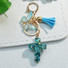 Gold-toned keychain featuring a blue resin butterfly charm and a turquoise cross pendant.