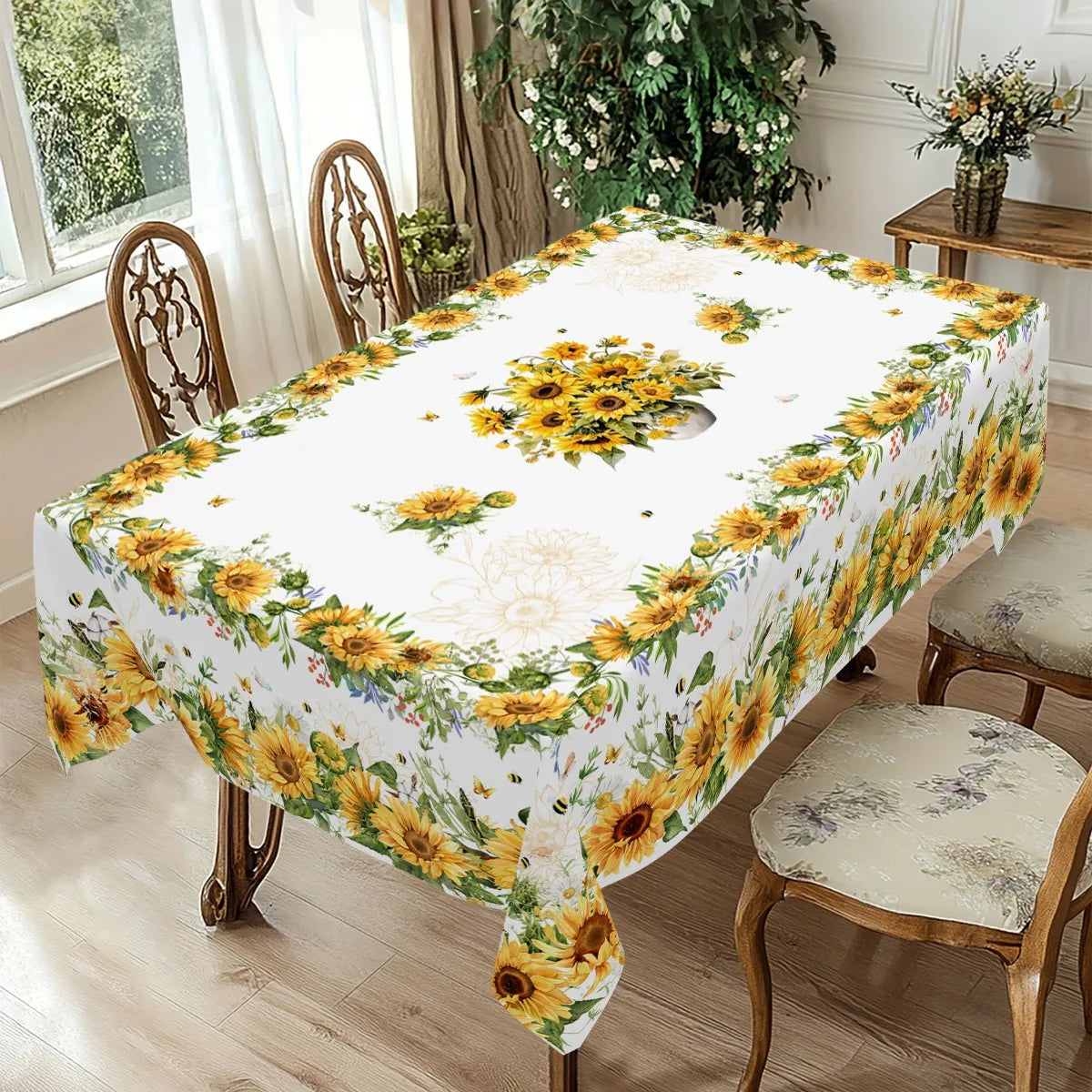 A white tablecloth with a yellow and green sunflower print set on a wooden dining table.
