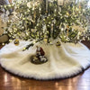 A lush green Christmas tree decorated with lights and ornaments sits atop a white faux fur skirt.