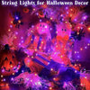 Purple and orange fairy string lights illuminating a Halloween decor scene with pumpkins and spooky foliage.