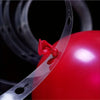 A close-up of a red balloon with a clear plastic strip and a red ribbon attached, set against a dark background.
