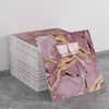 Marble peel-and-stick wall panels featuring pink and gold veining stacked on a gray surface