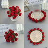 A bouquet of hand-crocheted red and green rose coasters displayed in clear glass bowls.