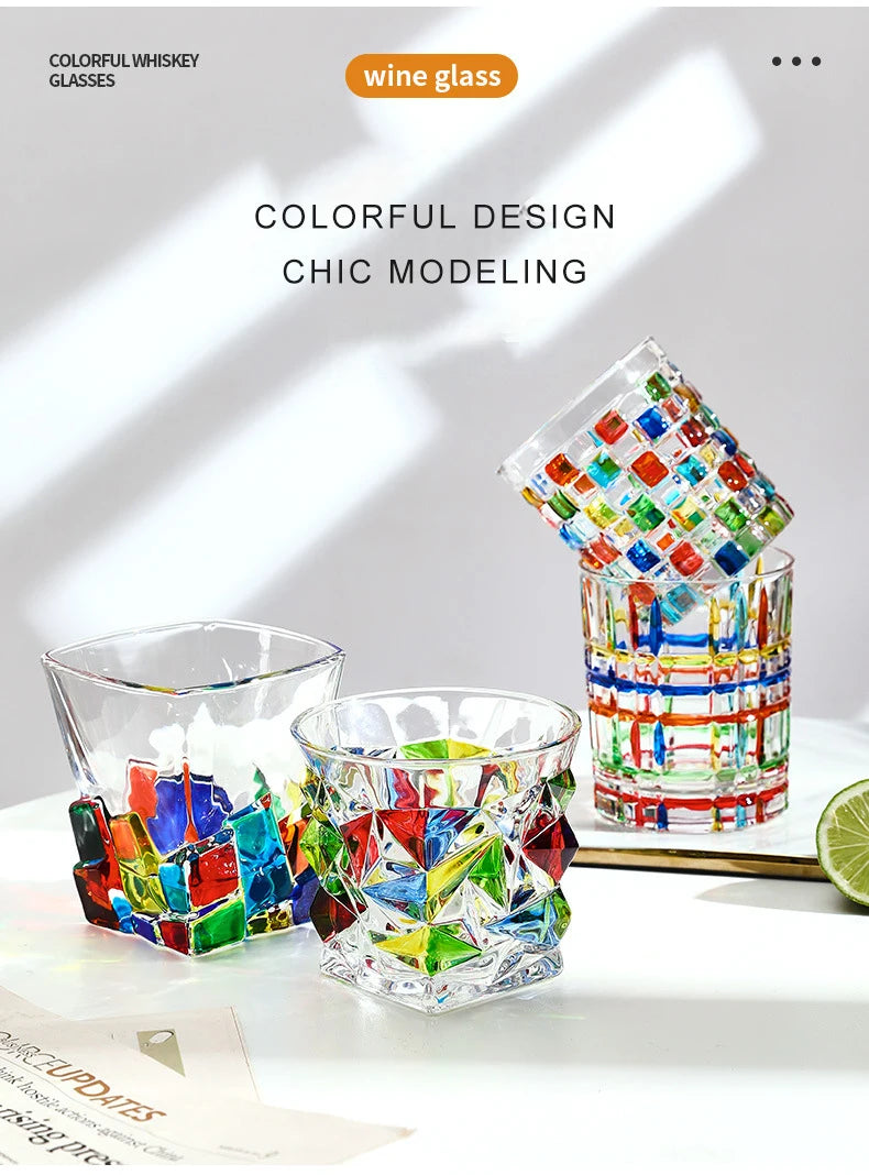 A collection of colorful faceted crystal whiskey glasses displayed on a white surface.