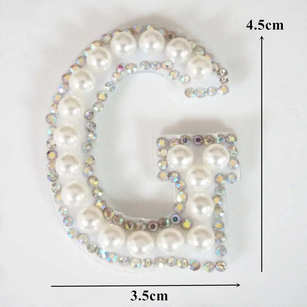 A rhinestone patch shaped like the letter G, featuring white and iridescent stones.