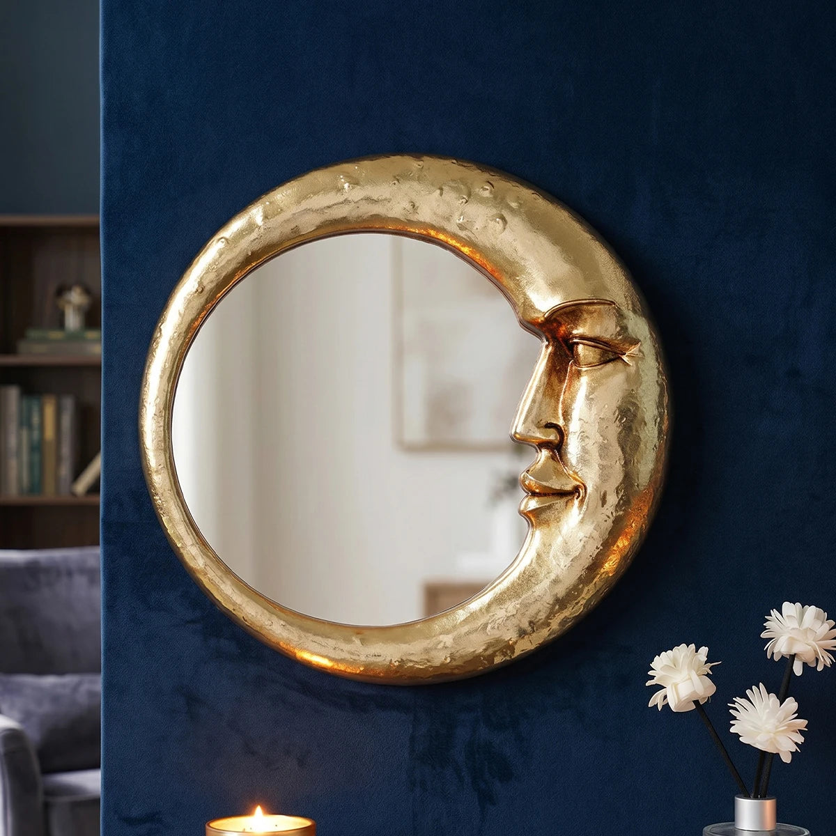A round, golden crescent decorative wall mirror mounted on a dark blue wall.