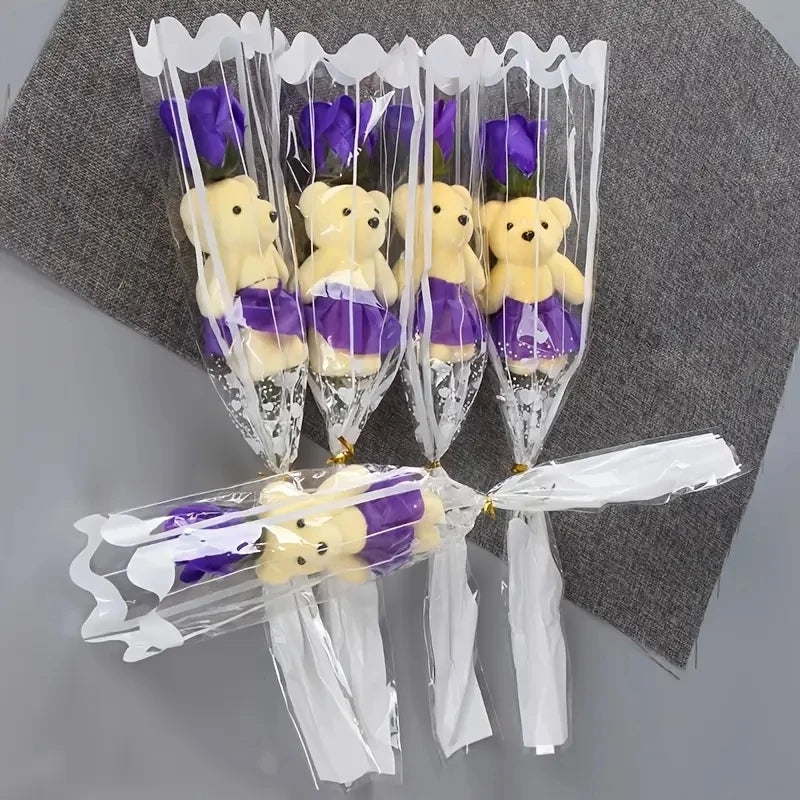 A bouquet of artificial rose soap featuring yellow teddy bears with purple accents, wrapped in clear cellophane.