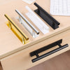 A collection of self-adhesive cabinet handles in gold, silver, and black finishes displayed on a wooden surface.