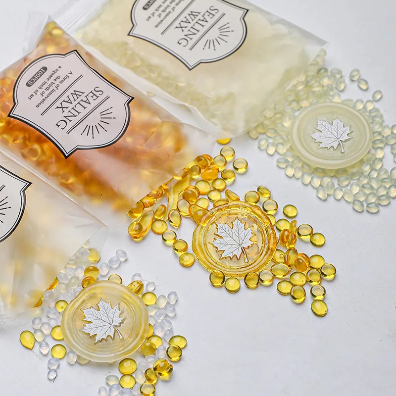 A collection of clear and yellow wax sealing beads and a wax sealing product are displayed on a white surface.