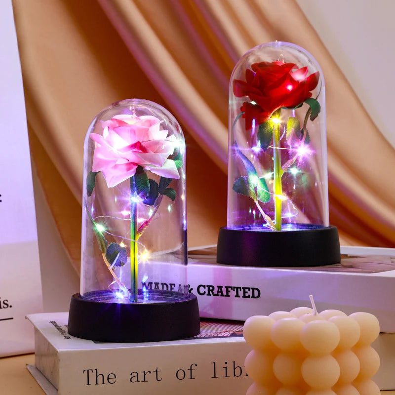 A glass dome display featuring a vibrant red rose illuminated with glowing lights.