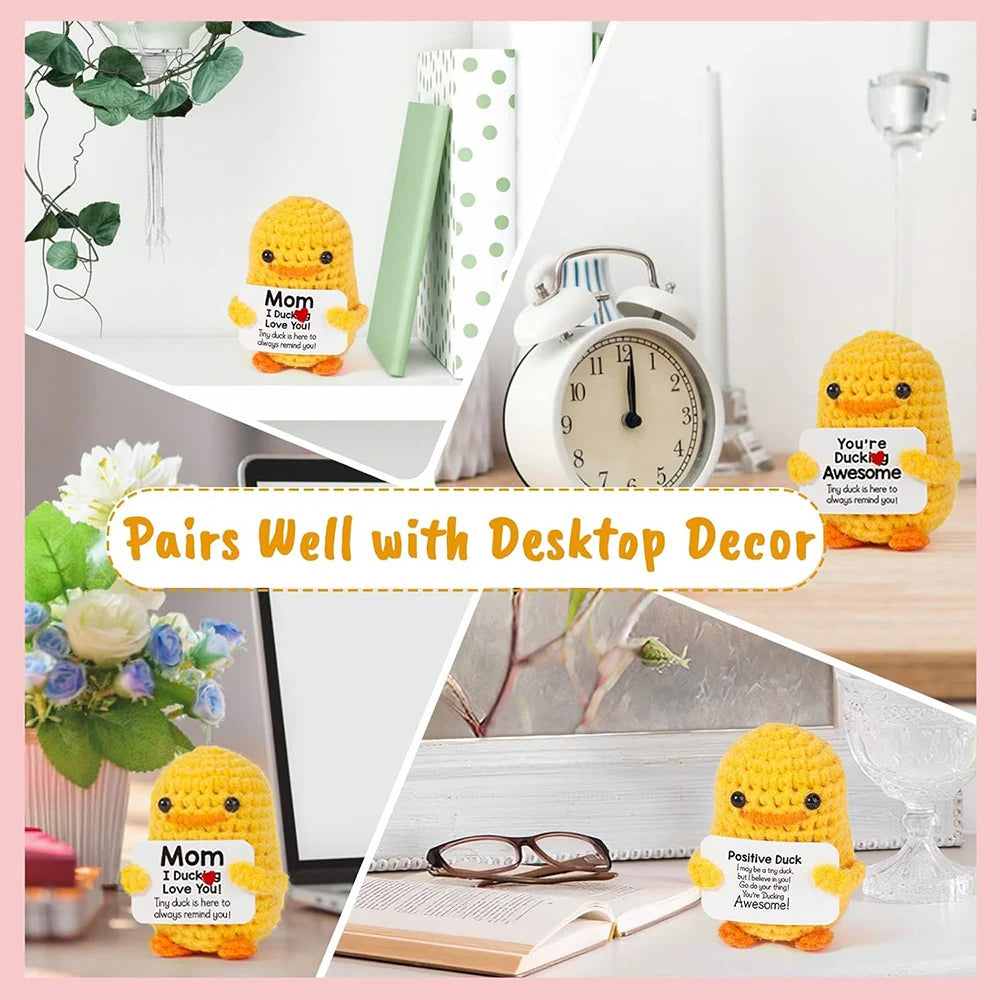 A yellow knitted duck plush toy paired with an inspirational card and various desktop decor items.