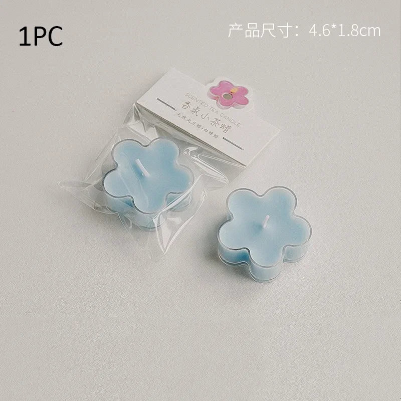 A single light blue flower-shaped soy wax tea light candle is packaged in clear plastic and displayed on a white background.