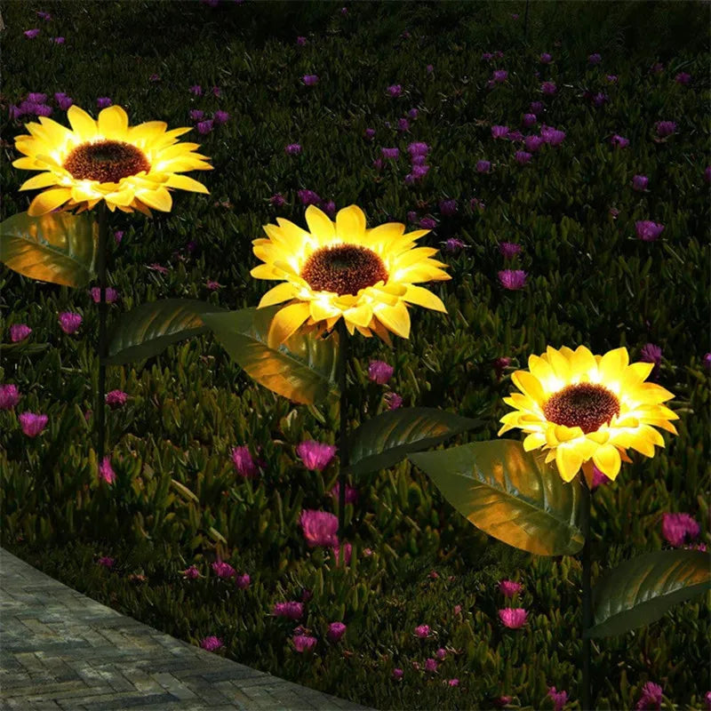A close-up of a bright yellow sunflower with a dark center growing in a garden setting.