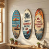 Decorative wooden surfboard wall art featuring tropical scenes and text on a white wall.
