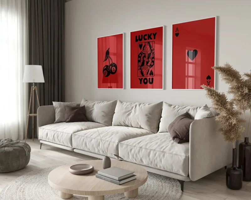 A modern living room features a light sofa and wooden coffee table with a set of red framed art prints displaying the words l