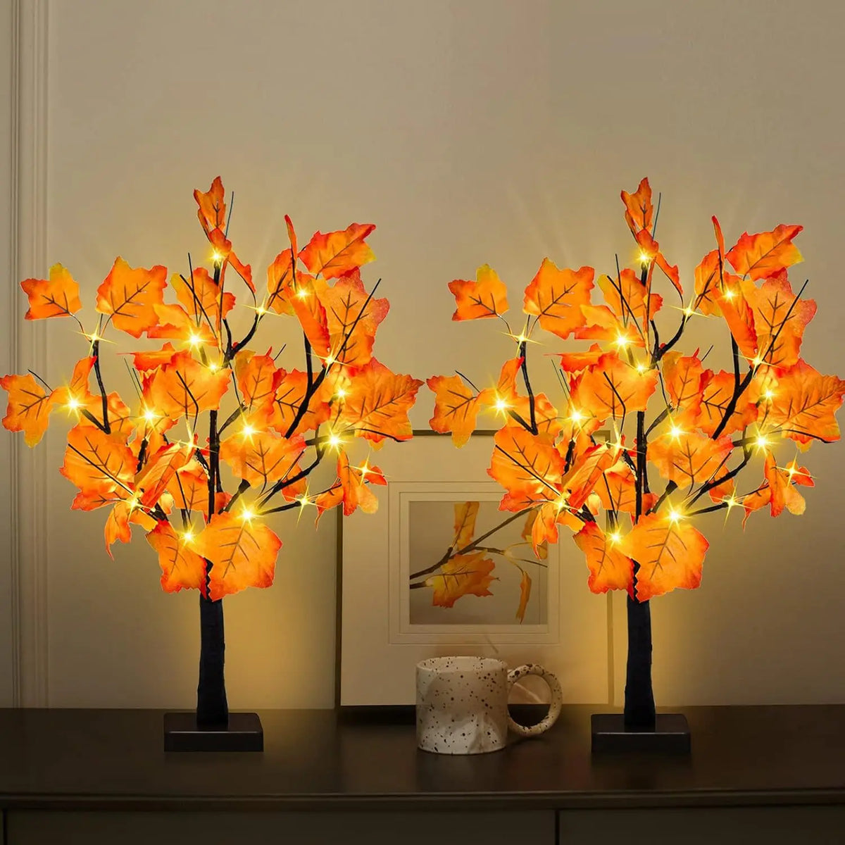 Warm glow maple tree decoration with autumn leaves and lights displayed on a dark table.