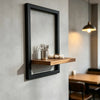 A black wooden floating wall shelf with a rectangular frame holds silverware and is mounted on a light gray wall.