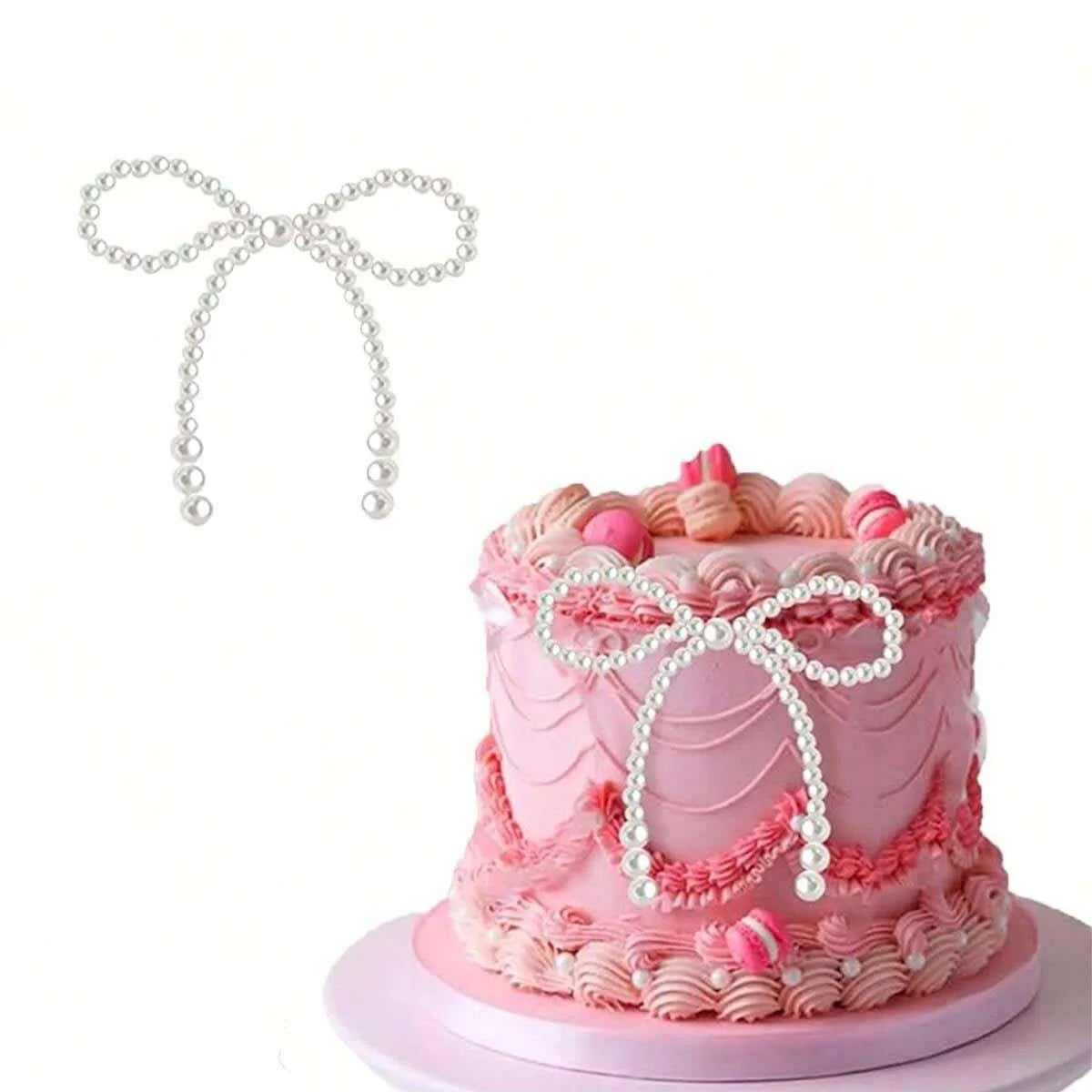 A pink tiered cake decorated with pink frosting and pearl bow accents, accompanied by a white pearl bow topper.