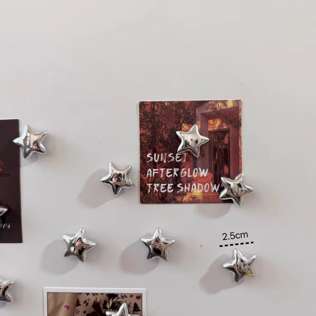 A set of decorative fridge magnets featuring silver star designs on a dark background.