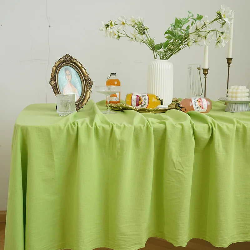A lime green tablecloth set for a dining or event, featuring a floral arrangement and decorative items.