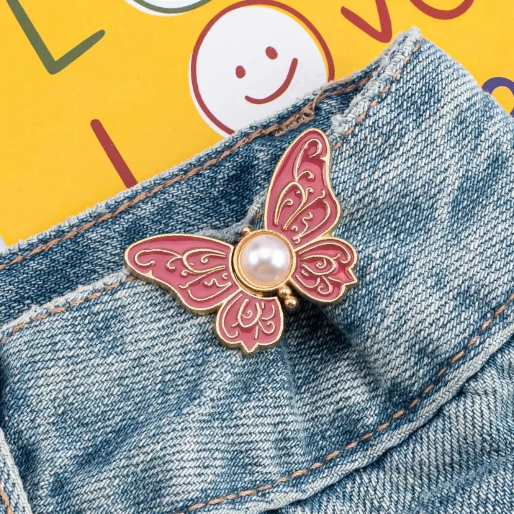 A pink butterfly clip with a pearl accent is shown attached to denim fabric.