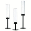 A set of three clear glass hurricane candle holders with black bases