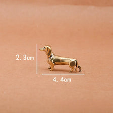 A brass dachshund figurine statue shown against a neutral background with dimension lines indicating its size.