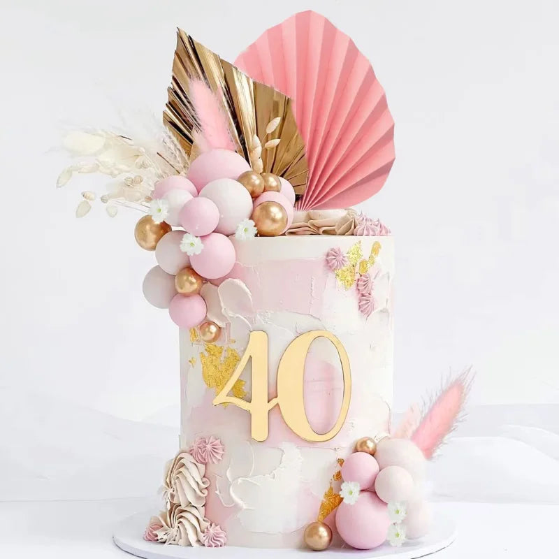 A four-tiered cake decorated with pink and gold flowers, including a palm leaf topper.