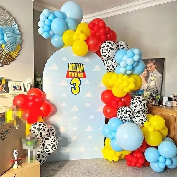 A display of latex balloons in blue, yellow, and red with cloud and cow print patterns for party decor.