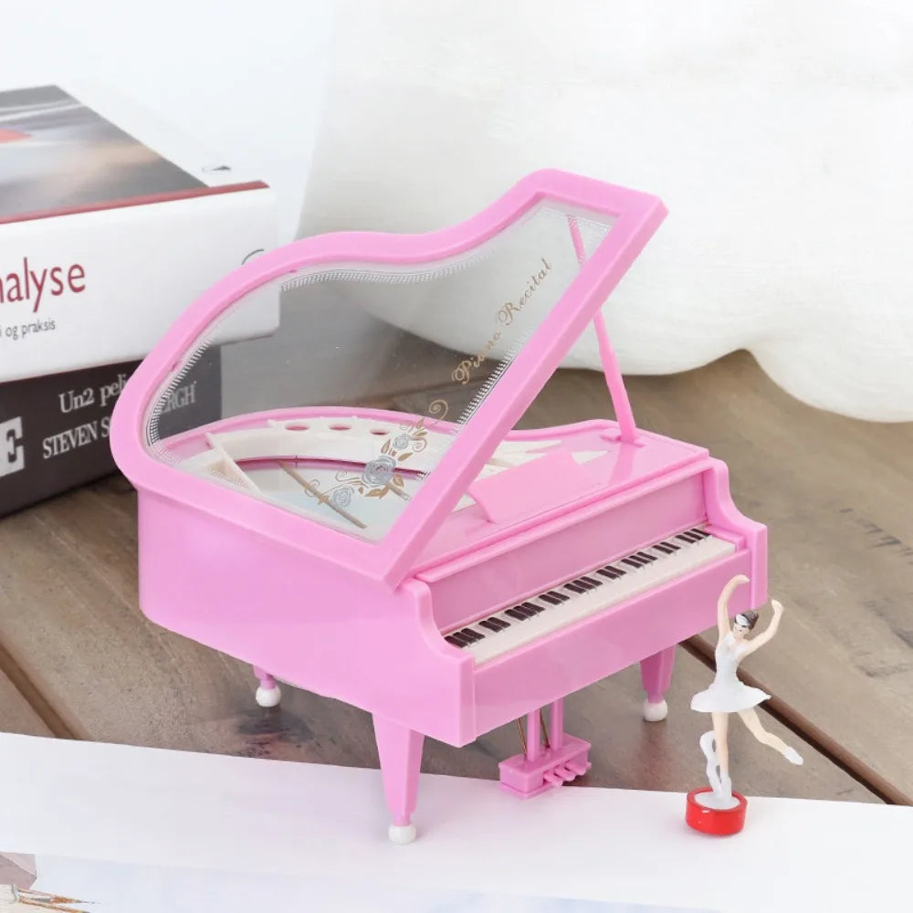 Pink hand-crank music box featuring a ballerina figurine and a piano keyboard.