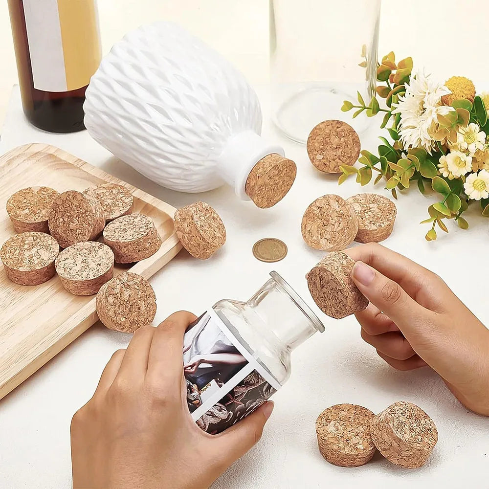Hands are placing adhesive cork circles onto a white ceramic bottle and wooden board for crafting.