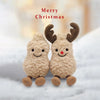 A pair of fluffy brown plush toys shaped like a peanut and reindeer with antlers resting on white snow.
