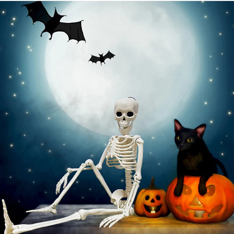 A white human skeleton decoration with movable bones is displayed in front of a large moon and a carved pumpkin.