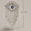 Macrame wall hanging featuring a white eye pendant with blue accents and long fringe.