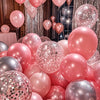 A close-up of various pink and silver confetti latex balloons arranged for party decorations.